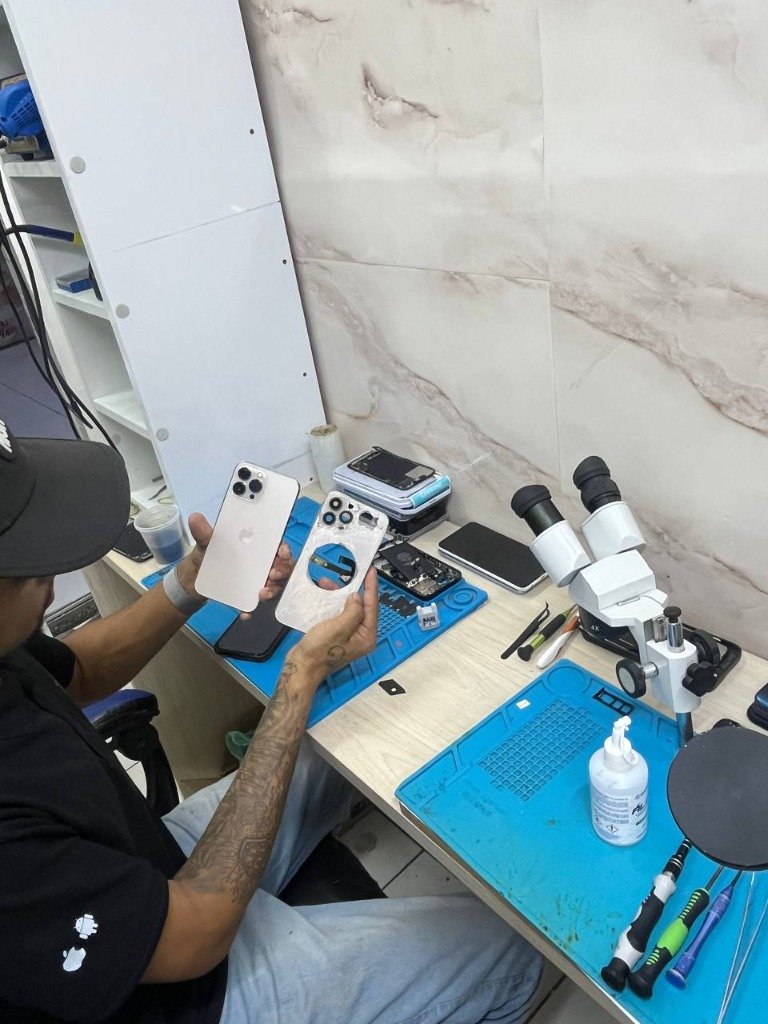 Técnico Tec Silva realizando reparo de iPhone na bancada com microscópio no Recreio